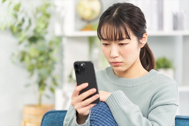スマホを見て困った表情の女性